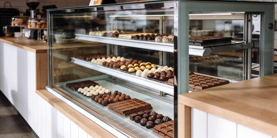 Chokladkyl med glasfront på ett kafé, med praliner och chokladkakor på flera hyllor