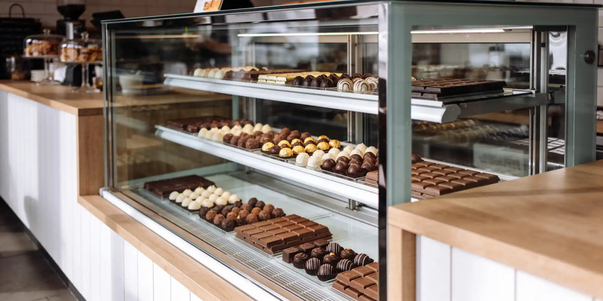 Chokladkyl med glasfront på ett kafé, med praliner och chokladkakor på flera hyllor