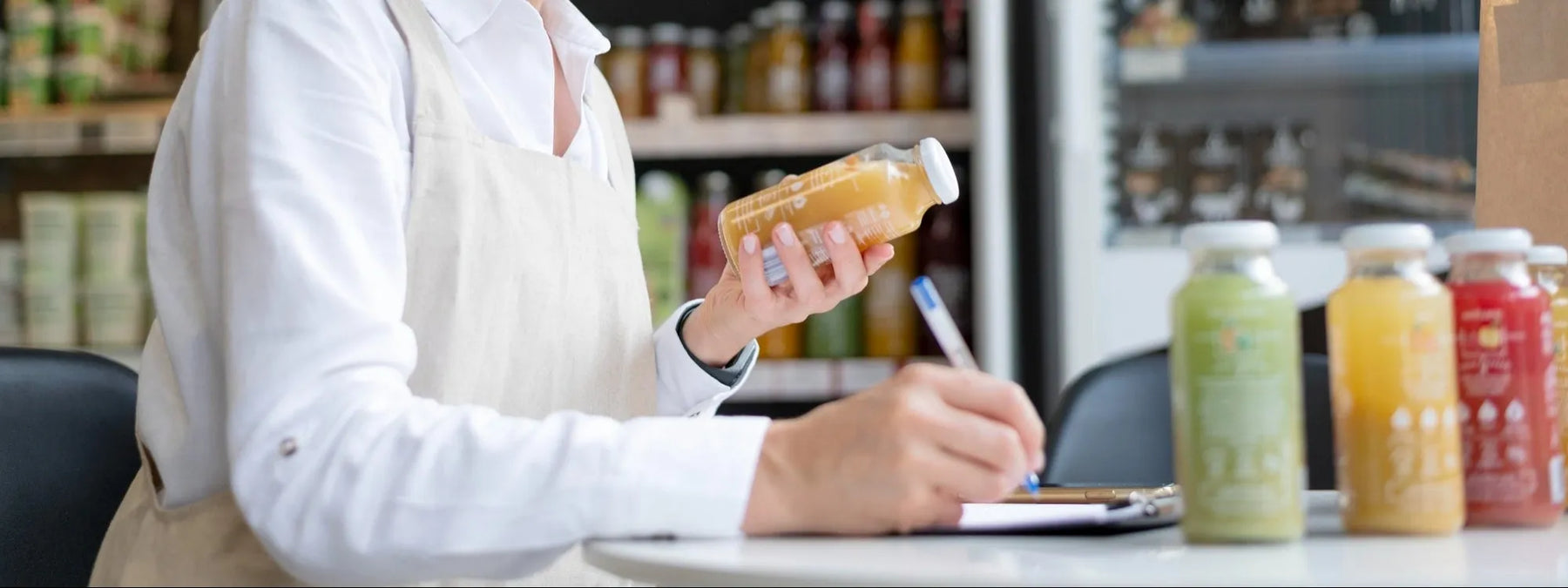 Butiksanställd kontrollerar och dokumenterar produkter som del av HACCP-rutiner i livsmedelsbutik