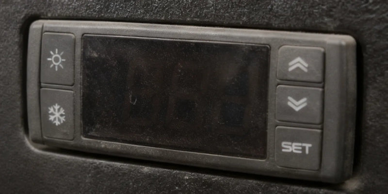 Trasig digital termostatpanel med sol och snöflingeikon