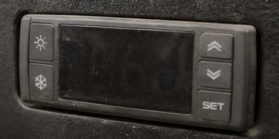 Trasig digital termostatpanel med sol och snöflingeikon