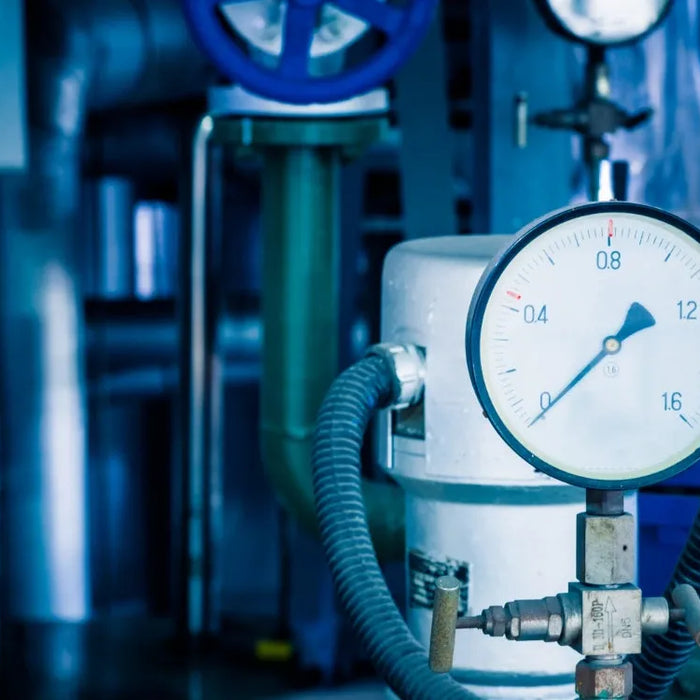 Närbild på tryckmätare i ett kylsystem för freon gas med rör och ventiler